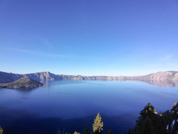 Scenic view of lake by mountains against clear blue sky