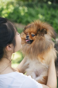 Young woman holding dog standing at park