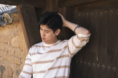 Portrait of young man standing against wall