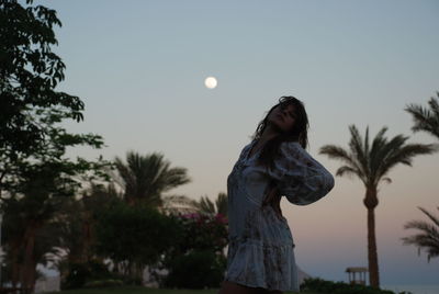 Woman standing by tree against sky