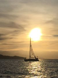 Sailboat sailing on sea against sky during sunset