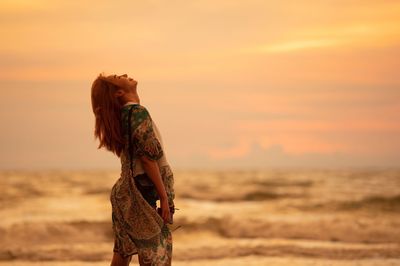 Woman standing on beach during sunset