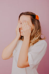 Portrait of woman covering face against wall