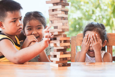 Sisters playing with wooden toy blocks on table while sitting in porch