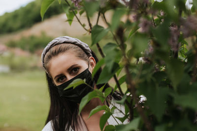 Woman with face mask looking behind the tree in nature