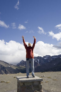 Portrait of woman with arms raised while standing on whistler mountain against sky