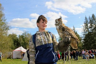 Low angle view of woman with eagle owl against sky
