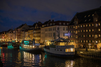 Boats in canal amidst buildings in city at night