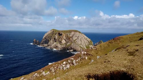 Scenic view of sea by cliff against sky