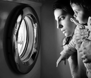 Side view of woman with boy looking at washing machine