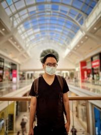 Portrait of young man standing against skylight and architecture 