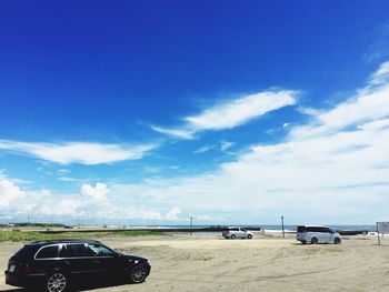 View of car on sand against blue sky