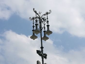 Low angle view of weather vane against cloudy sky