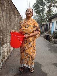 Woman with umbrella standing against built structure