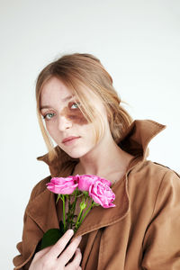 Portrait of beautiful woman with pink flower against white background