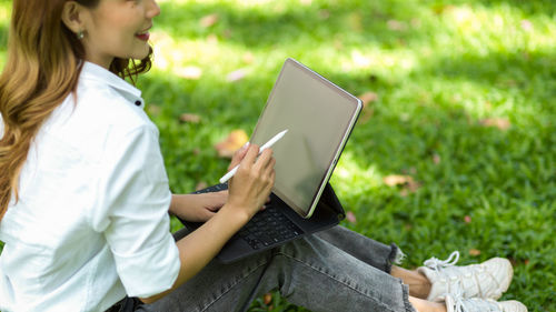 Low section of woman using laptop at park