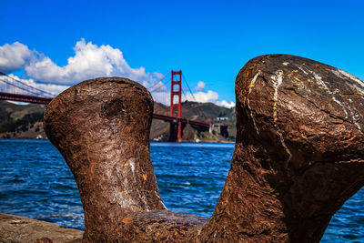 View of rusty bridge over sea against blue sky
