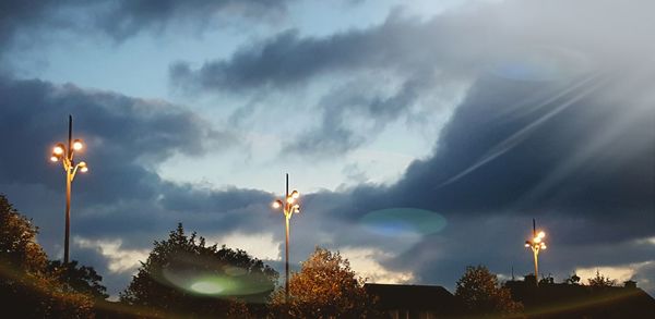 Low angle view of illuminated street light against cloudy sky