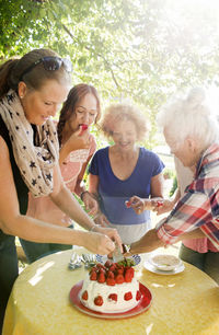 Four women preparing strawberry cake in garden