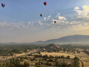 Hot air balloons flying over landscape against sky