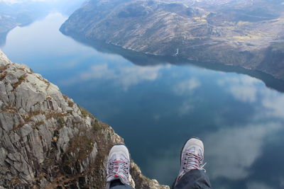 Low section of person on rock against sky