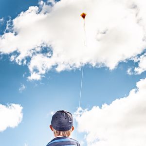 Child with kite against a cloudy sky