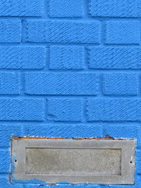 Close-up view of blue wall with metal letterbox