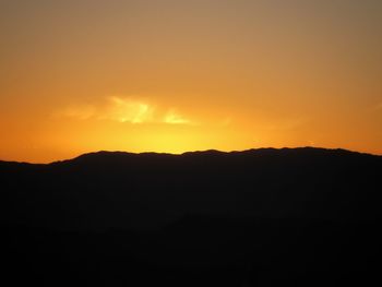 Scenic view of silhouette mountains against orange sky