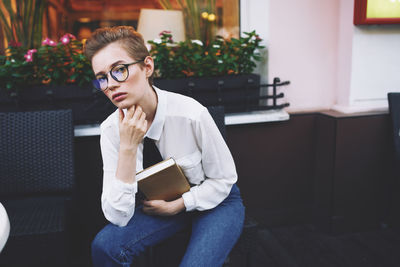 Young woman sitting on book at home