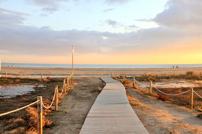 Wooden pier on sea against sky during sunset