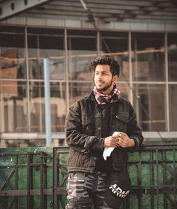 Portrait of young man standing against railing