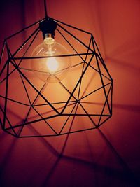 Close-up of illuminated light bulb hanging from ceiling