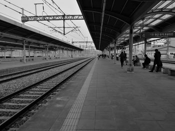 People waiting at railroad station platform against sky