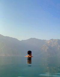 Rear view of man on mountain against clear sky