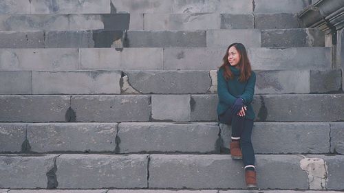 Portrait of young woman standing against brick wall