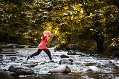 Woman standing on rock by river in forest