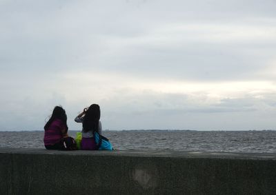 Rear view of people sitting on beach