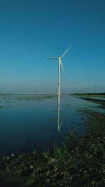 Wind turbines on landscape against clear blue sky