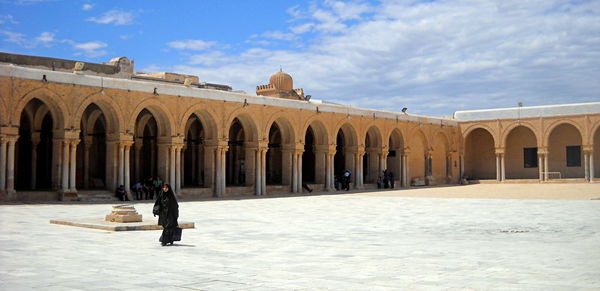 Man walking on snow covered building against sky