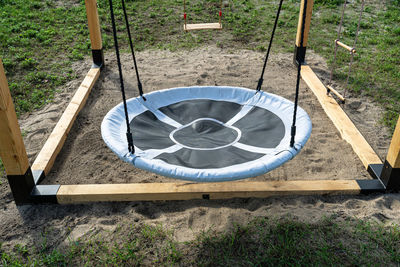 A modern cubic playground made of wooden logs and metal corners, a visible rocker and a nest.