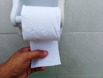 Midsection of person holding paper against white wall