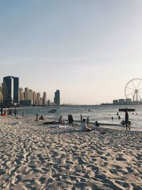 People on beach against sky in city