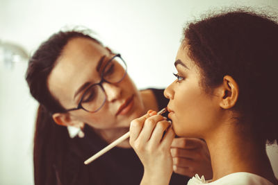 Side view of young woman blowing bubbles at home