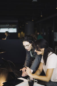 Young woman using mobile phone while sitting on table