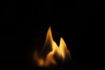 Close-up of burning candle against black background