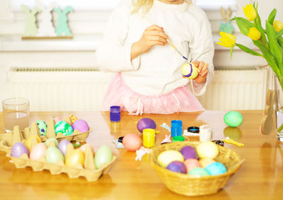 A little girl painting eggs for easter on the wooden table at home. preparation for easter.