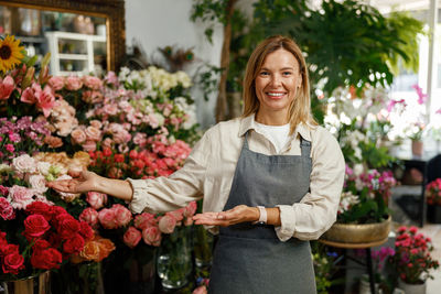 Portrait of smiling young woman standing in greenhouse