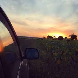 Car on landscape against sky during sunset