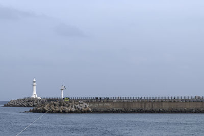 Lighthouse by sea against sky