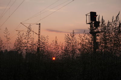 Low angle view of electricity pylon against sky during sunset